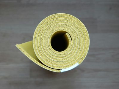 Black yoga mat rolled up on a dark floor.