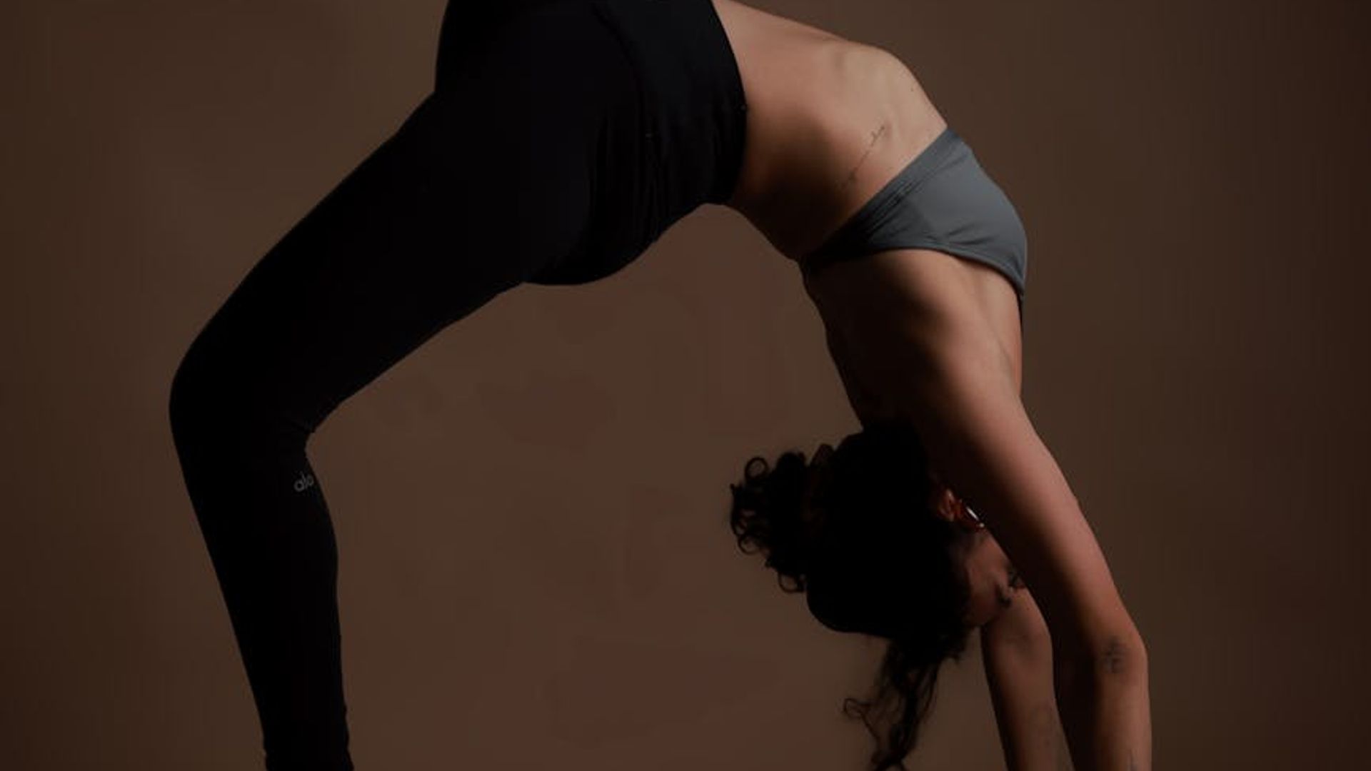 Person practicing yoga in a dark aesthetic studio with soft teal lighting.